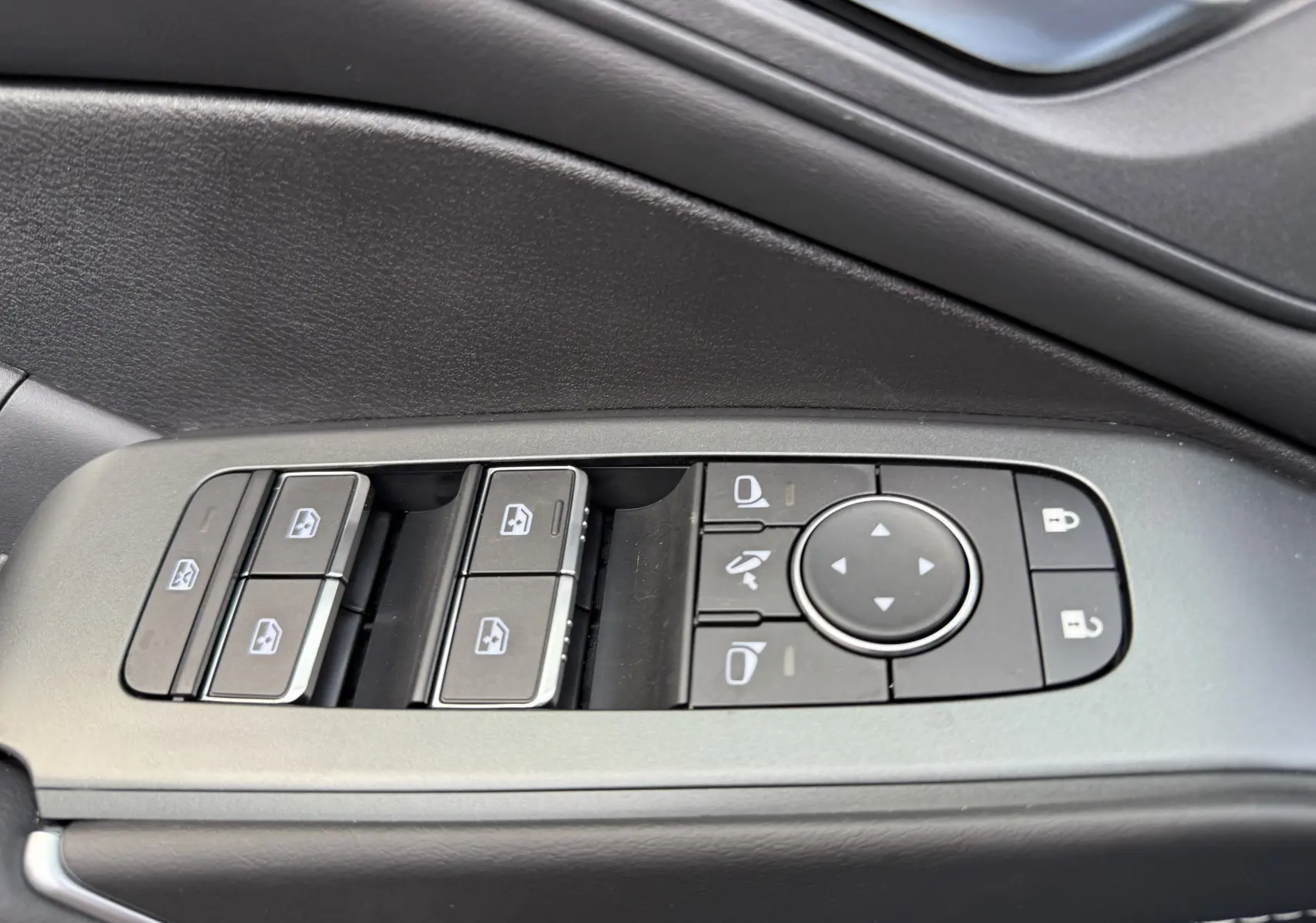 Gros plan sur les commandes des vitres et des rétroviseurs côté gauche intérieur du Nissan Qashqai gris Squale Metal 2025.