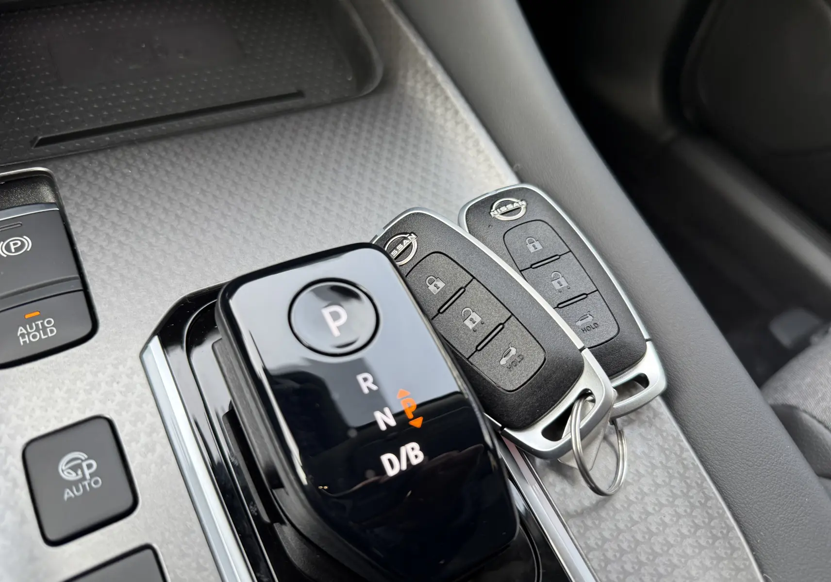 Gros plan sur la console centrale du Nissan Qashqai 2025 gris, avec la boîte auto et deux clés Nissan posées.