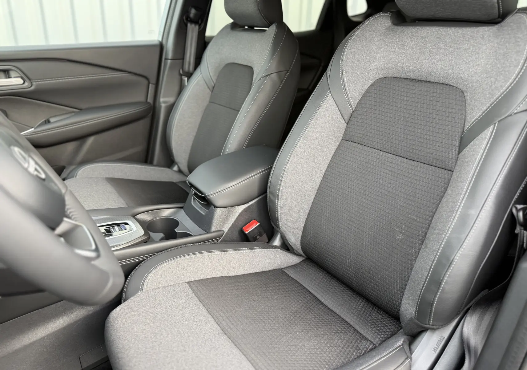Vue intérieure rapprochée des sièges avant gris clair et noir avec surpiqûres blanches du Nissan Qashqai 2025.