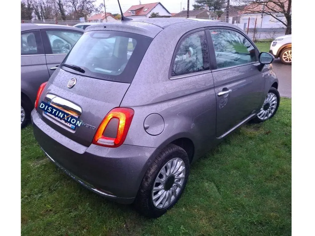 Vue 3/4 arrière droite d'une Fiat 500 gris Electroclash 2022 avec feux arrière allumés sur pelouse humide.