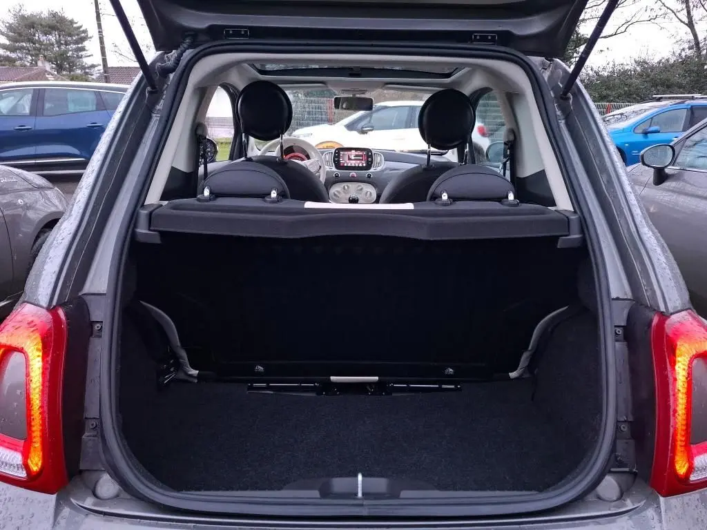 Vue arrière ouverte sur le coffre d'une FIAT 500 gris Electroclash avec intérieur et tableau de bord visibles.