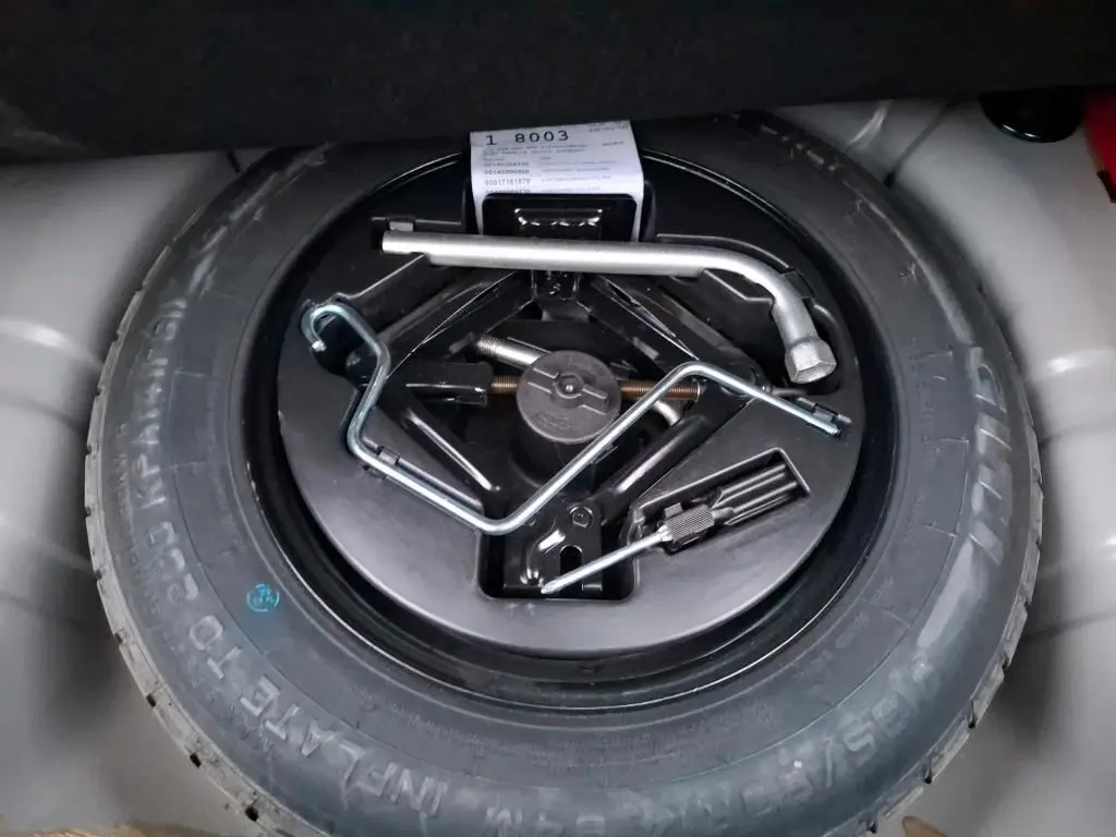 Gros plan sur la roue de secours et les outils de bord dans le coffre d'une FIAT 500 Gris Electroclash 2022.