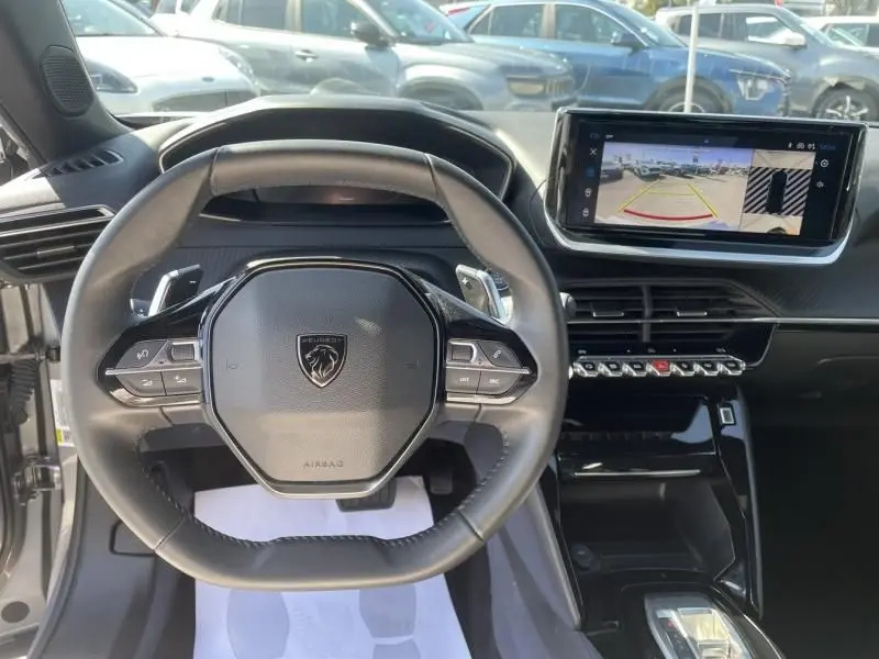 Vue intérieure centrée sur le volant du Peugeot 2008 gris métal 2025 avec écran tactile et commandes au volant.