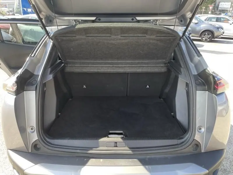 Coffre ouvert vu de l'arrière d'un Peugeot 2008 gris métal 2025, version hybride essence Allure e-DCS6.