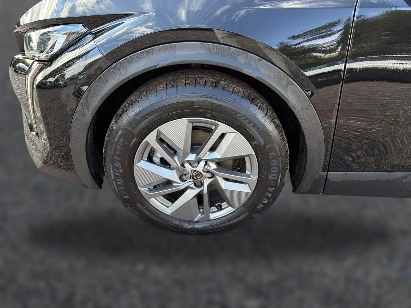 Gros plan sur la roue avant gauche d'une Peugeot 408 noire, mettant en valeur la jante alu au design moderne et le passage de roue.