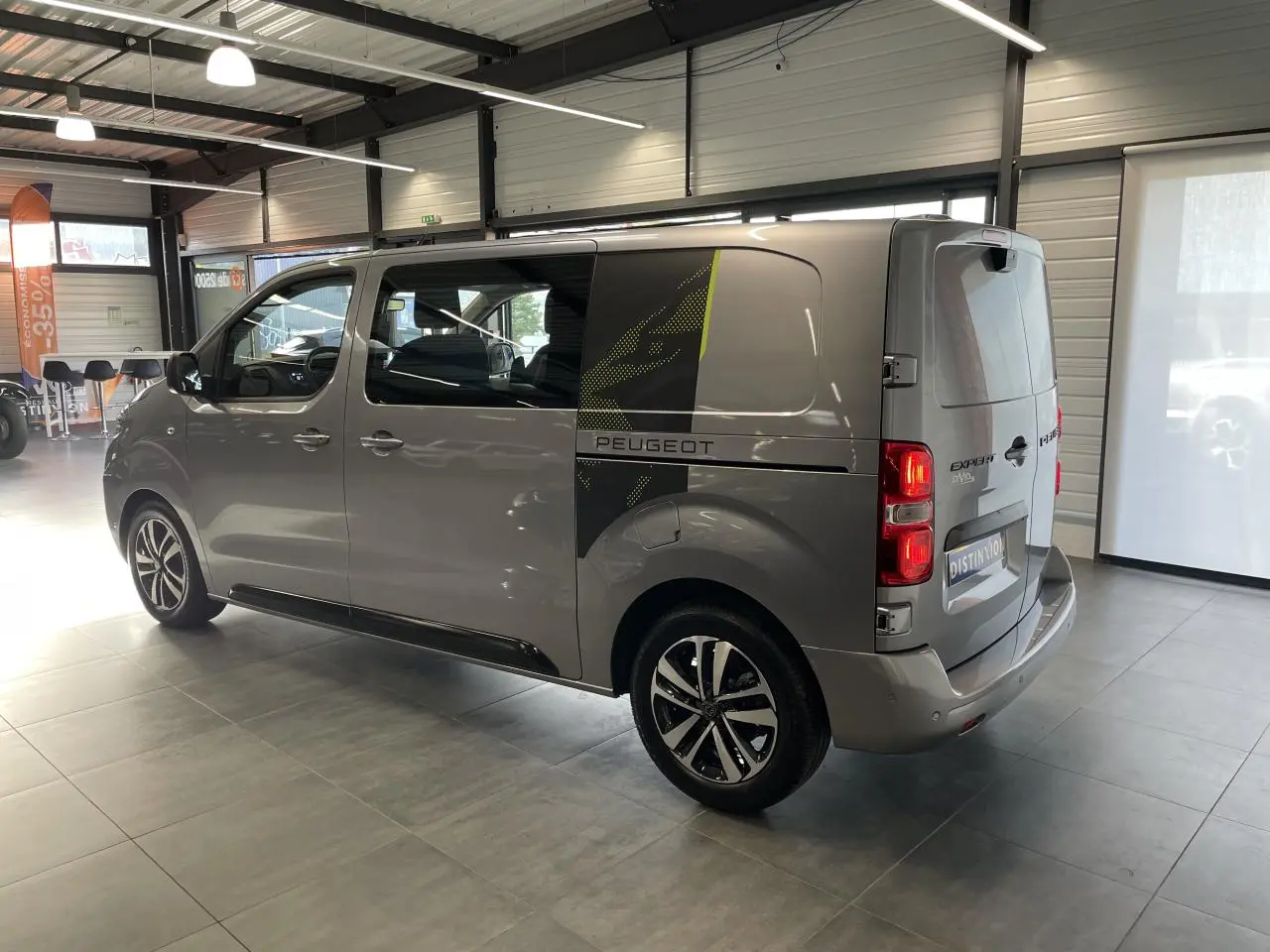 Peugeot Expert Fourgon gris Artense en 3/4 arrière droit avec décor noir et vert sur la porte latérale.