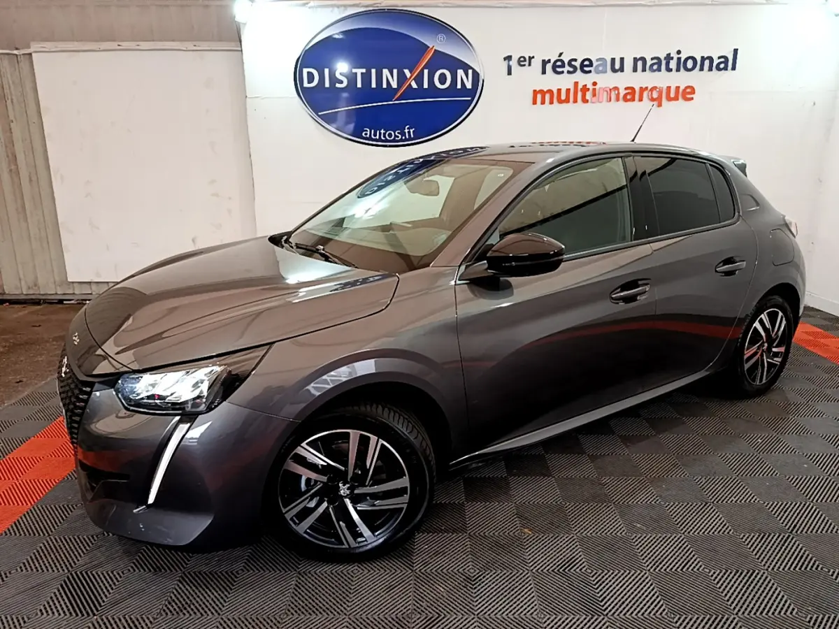 Peugeot 208 gris foncé vue 3/4 avant droit, avec jantes alliage et phares LED distinctifs.