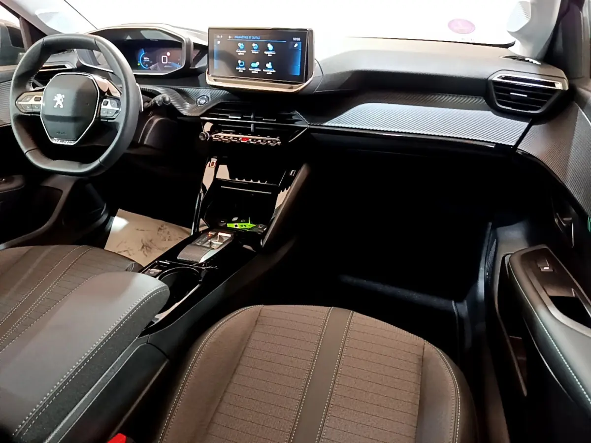Vue intérieure avant droite du Peugeot 208 2022, tableau de bord noir avec écran tactile central et volant cuir multifonctions.