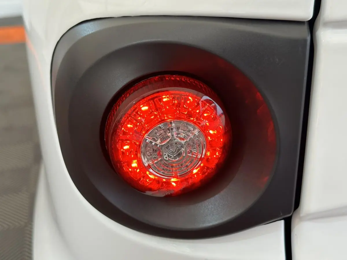 Gros plan sur le feu arrière rouge circulaire du côté gauche de l'AIXAM MINAUTO E ACCESS blanc 2025 électrique.