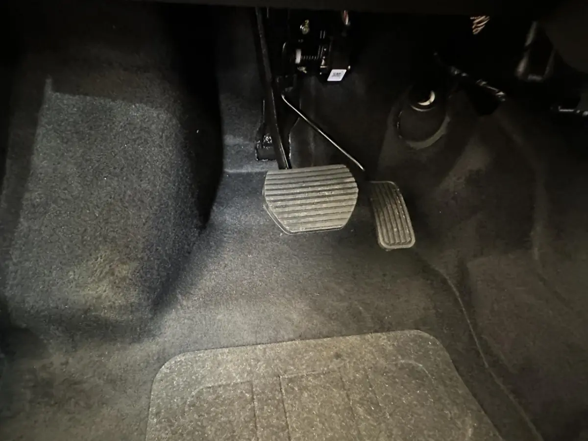 Vue rapprochée des pédales d'accélérateur et de frein sur le côté conducteur de l'AIXAM MINAUTO E ACCESS 2025 blanc électrique.