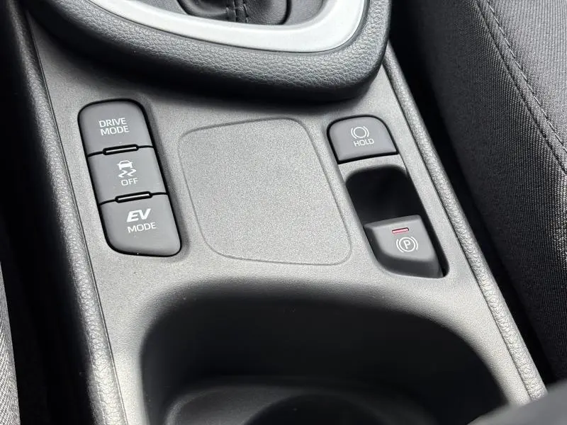 Gros plan sur la console centrale noire de la Toyota Yaris 116h Dynamic 5p MC24 avec boutons Drive Mode et frein électrique
