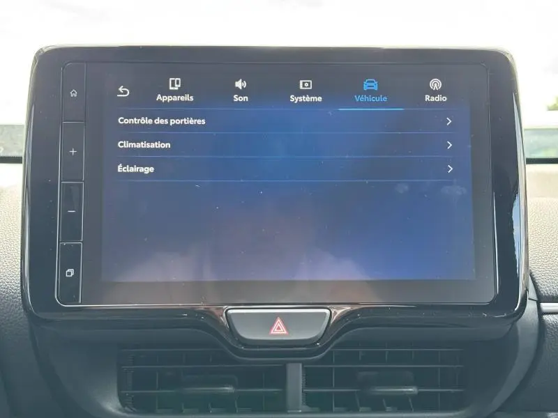 Écran tactile central affichant les réglages du véhicule sur une Toyota Yaris blanche, vue intérieure frontale.