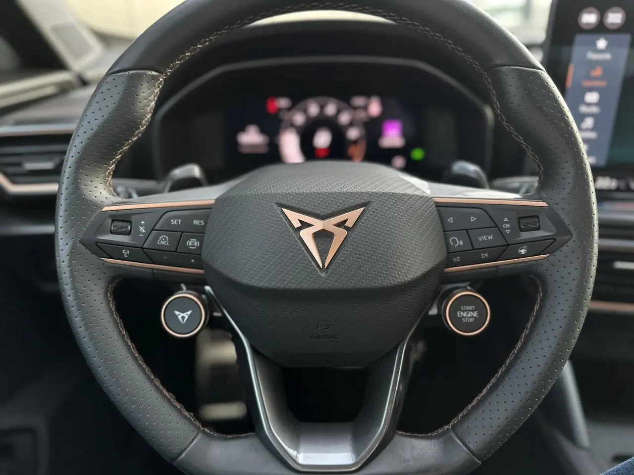 Gros plan sur le volant cuir perforé noir avec logo CUPRA cuivré et commandes multifonctions du Formentor Blanc Neige 2025.