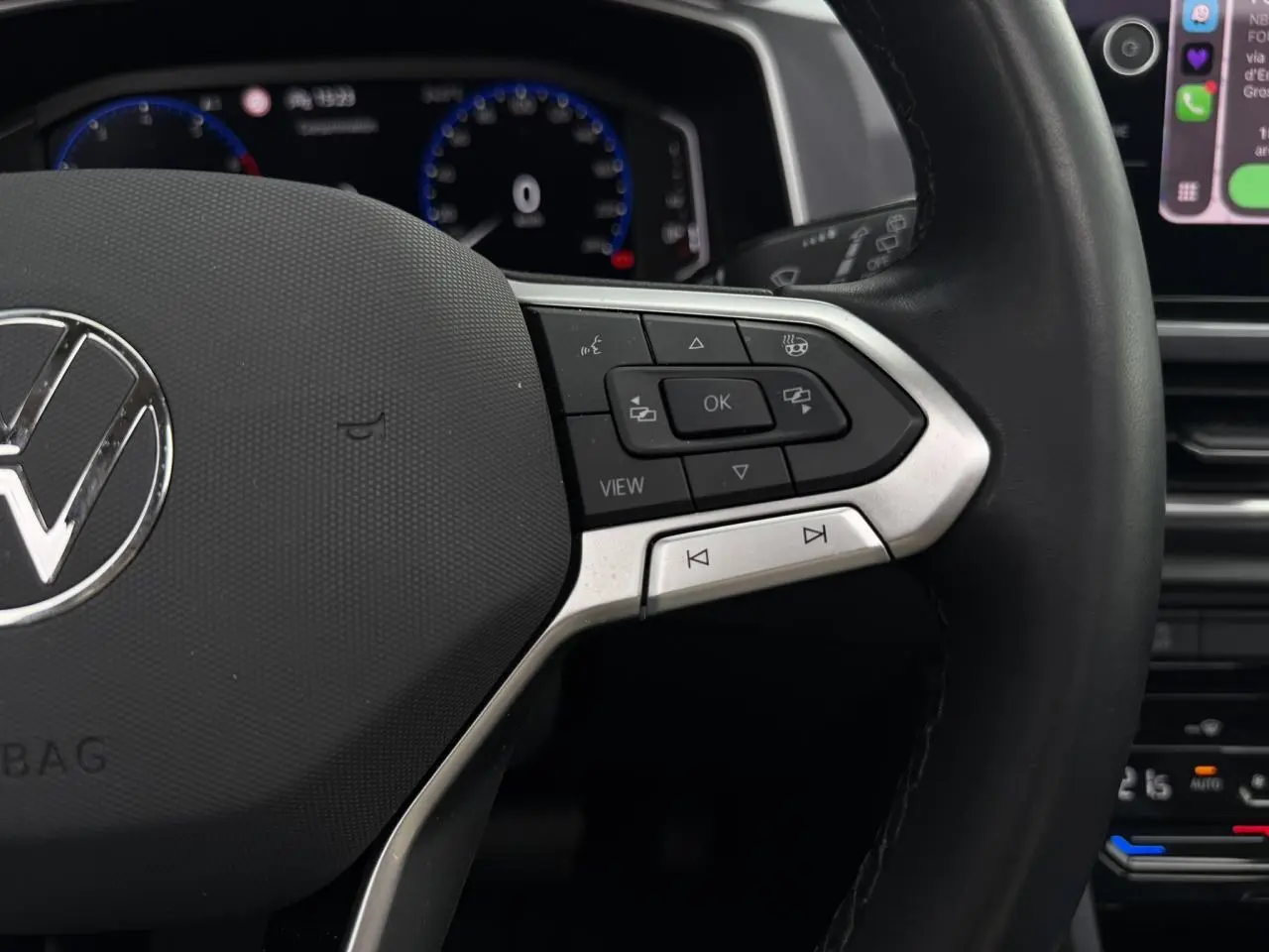 Gros plan sur le volant multifonction noir avec commandes intégrées du Volkswagen T-Roc 2024, tableau de bord numérique en arrière-plan.