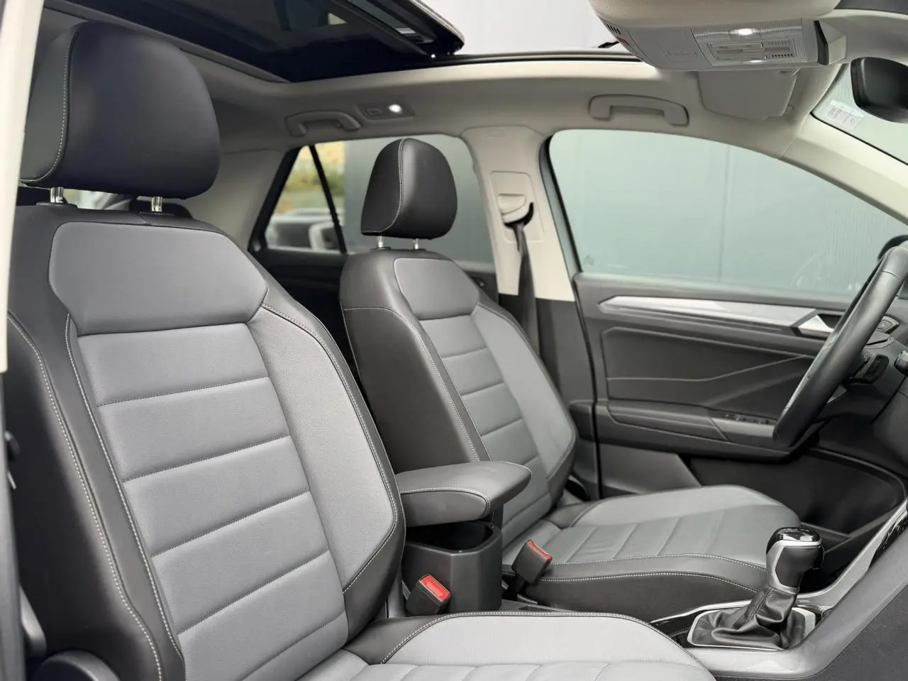 Vue intérieure des sièges avant en cuir gris platinium du Volkswagen T-Roc 2024 avec toit ouvrant panoramique.