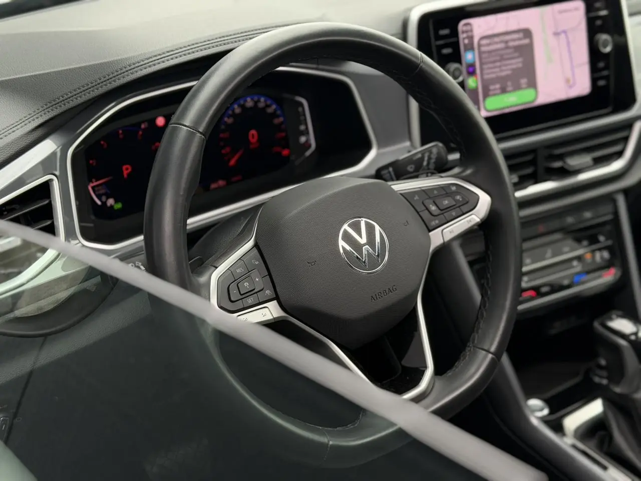 Vue intérieure centrée sur le volant en cuir noir du Volkswagen T-Roc 2024 avec tableau de bord numérique et écran tactile.