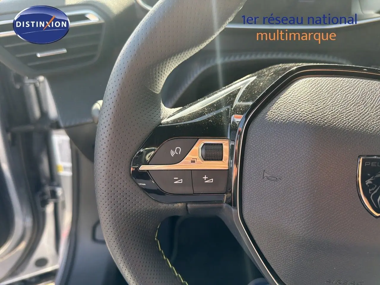 Gros plan sur le volant cuir perforé du Peugeot 2008 1.2 Hybrid 145 GT, avec commandes intégrées et logo central.