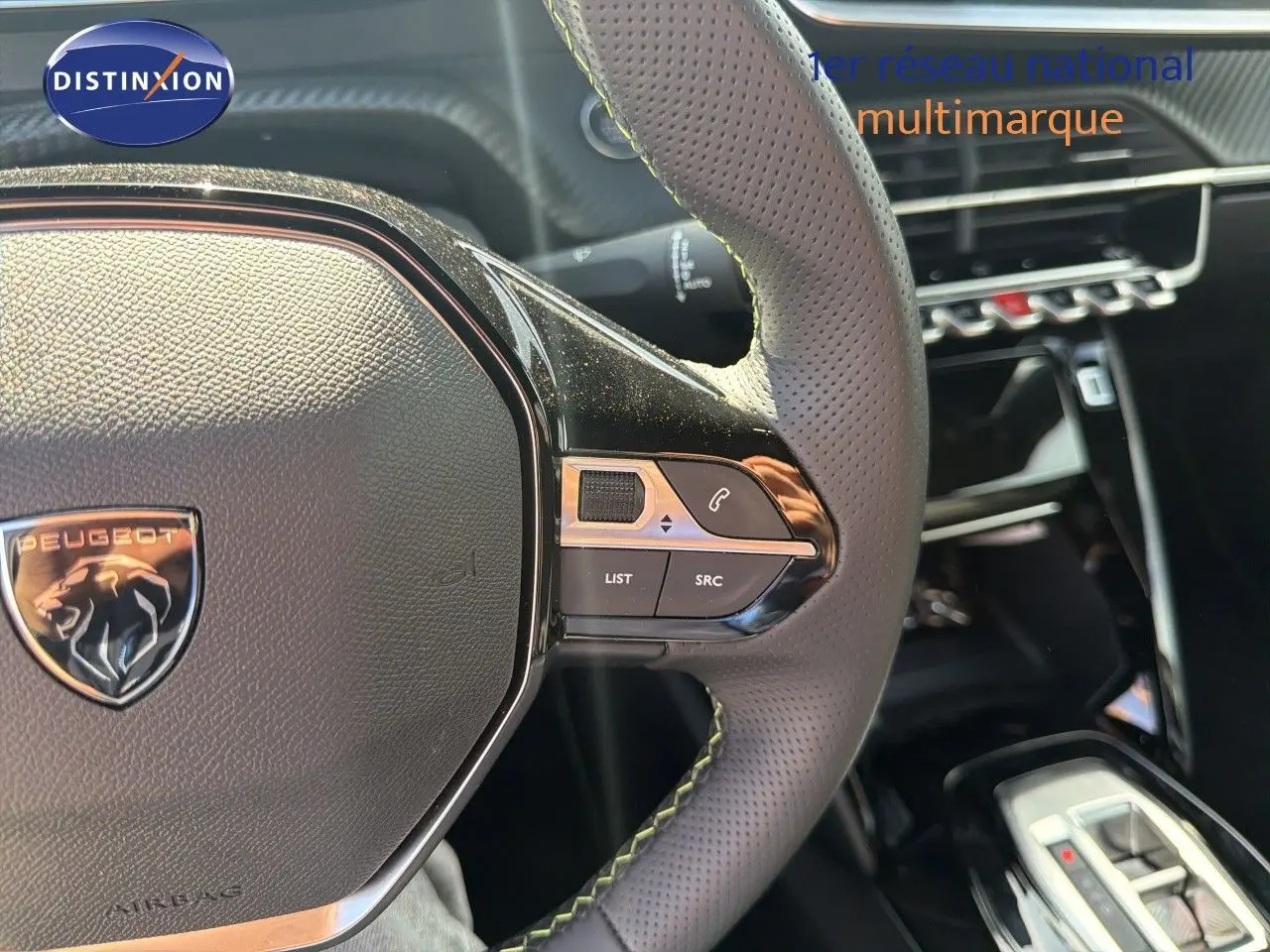Gros plan sur le volant perforé de la Peugeot 2008 1.2 Hybrid 145 GT avec commandes intégrées, intérieur noir.