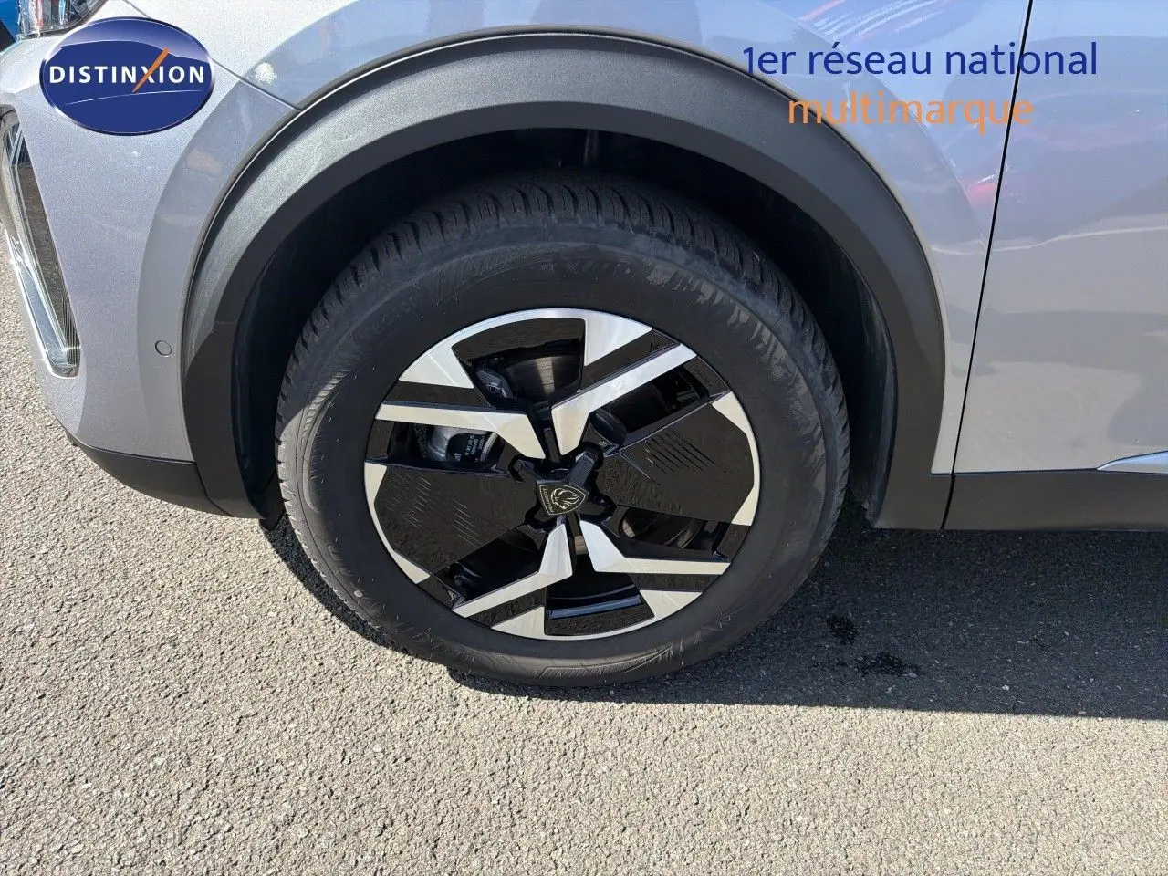 Gros plan sur la roue avant gauche du Peugeot 2008 gris Artense avec jante noire et argentée en extérieur.