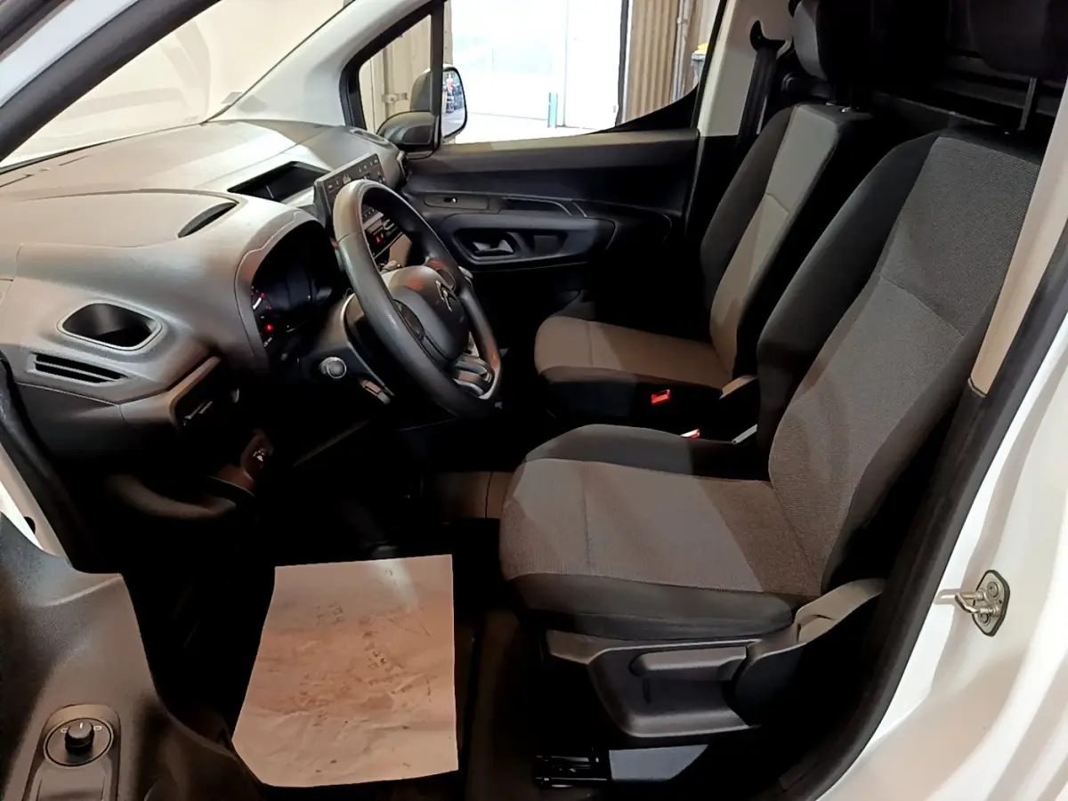 Intérieur côté conducteur du Citroën Berlingo blanc 2021, montrant le tableau de bord et sièges en tissu gris.