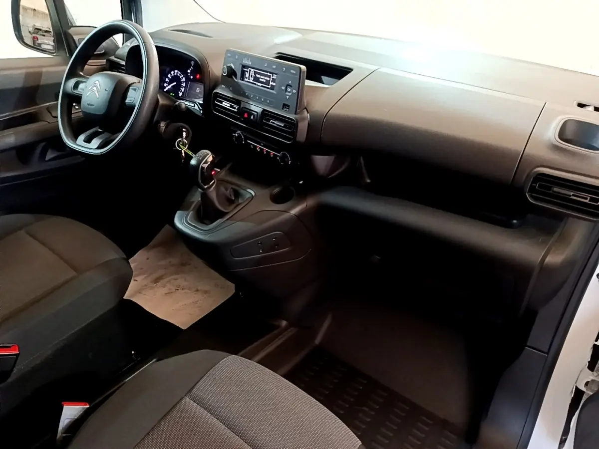 Vue intérieure côté conducteur du Citroën Berlingo blanc 2021, tableau de bord avec écran tactile et volant multifonction.