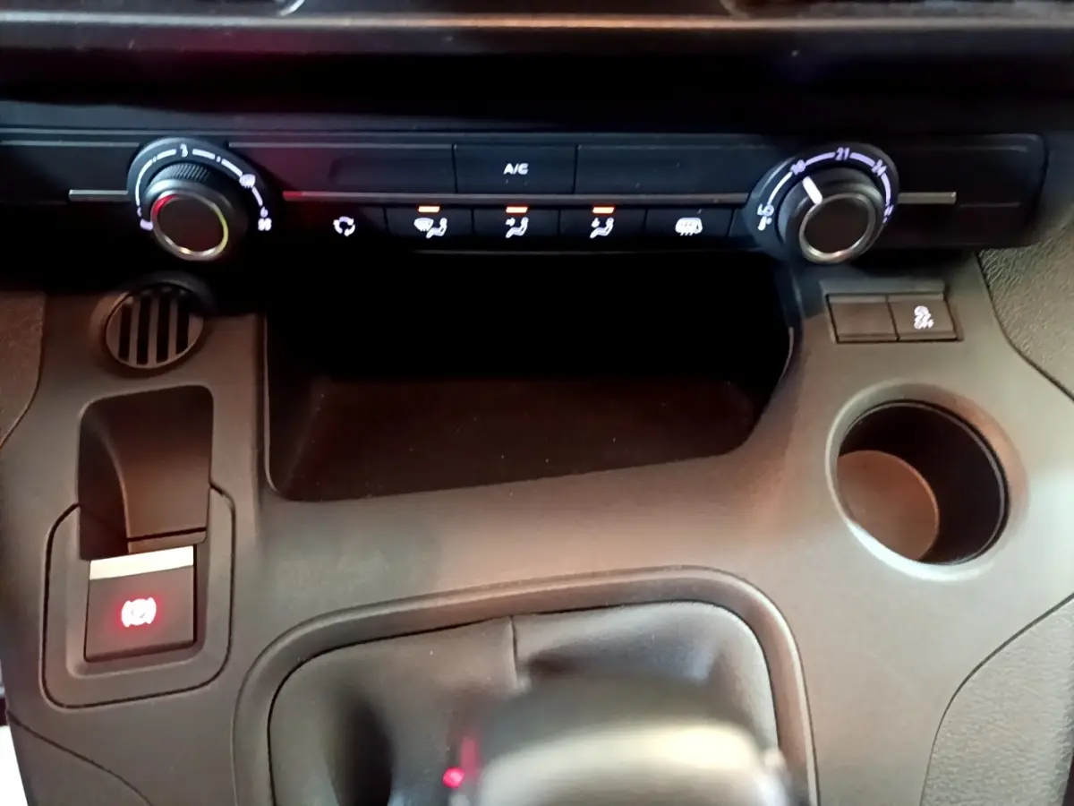 Vue rapprochée de la console centrale noire du Citroën Berlingo 2021 avec commandes climatisation et frein à main électrique.