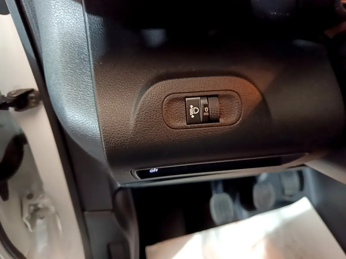 Gros plan sur le réglage manuel des phares dans l'habitacle du Citroën Berlingo blanc 2021 côté conducteur.
