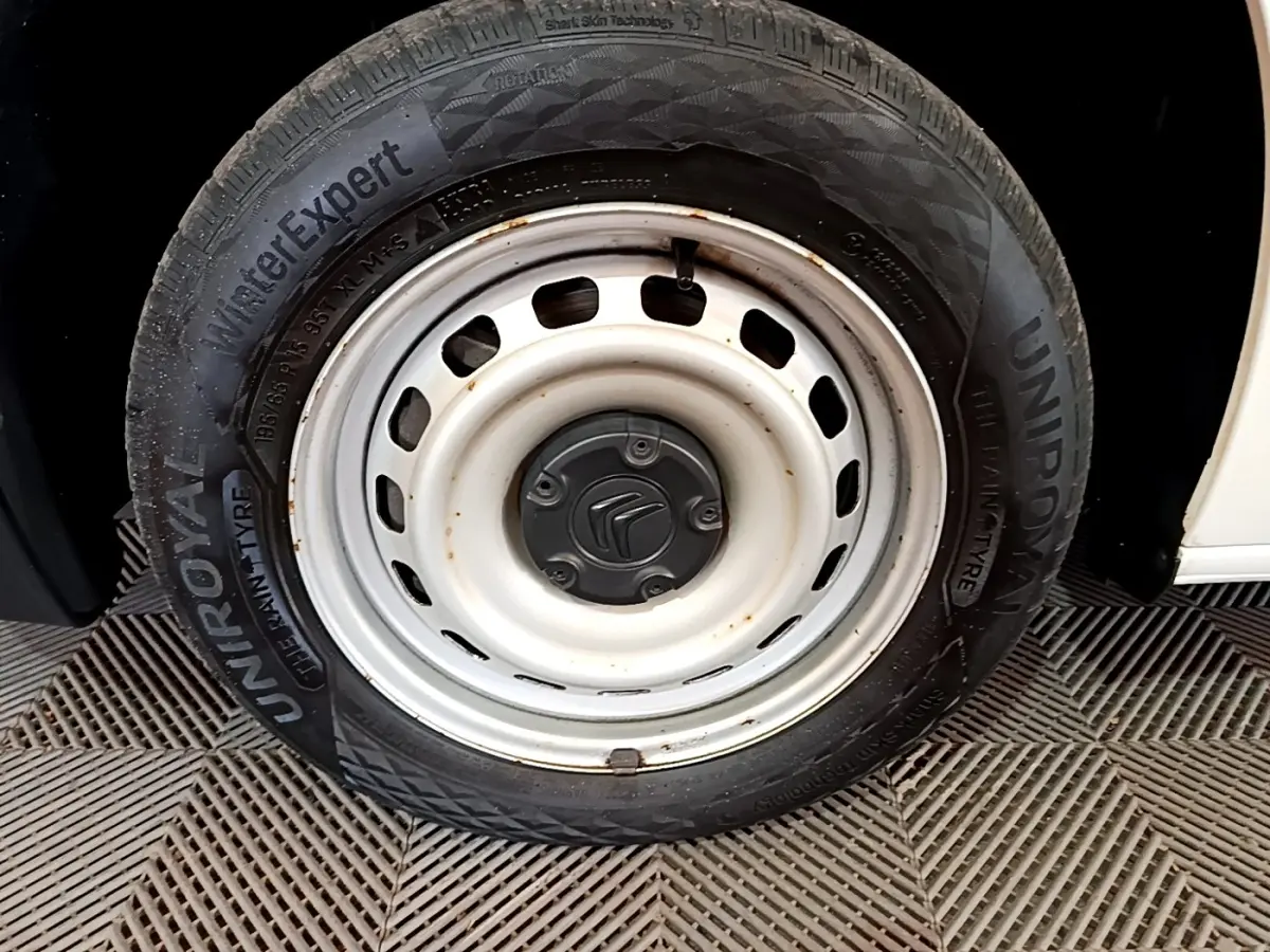 Gros plan sur la roue avant droite blanche du Citroën Berlingo 2021, avec jante acier et logo Citroën au centre.