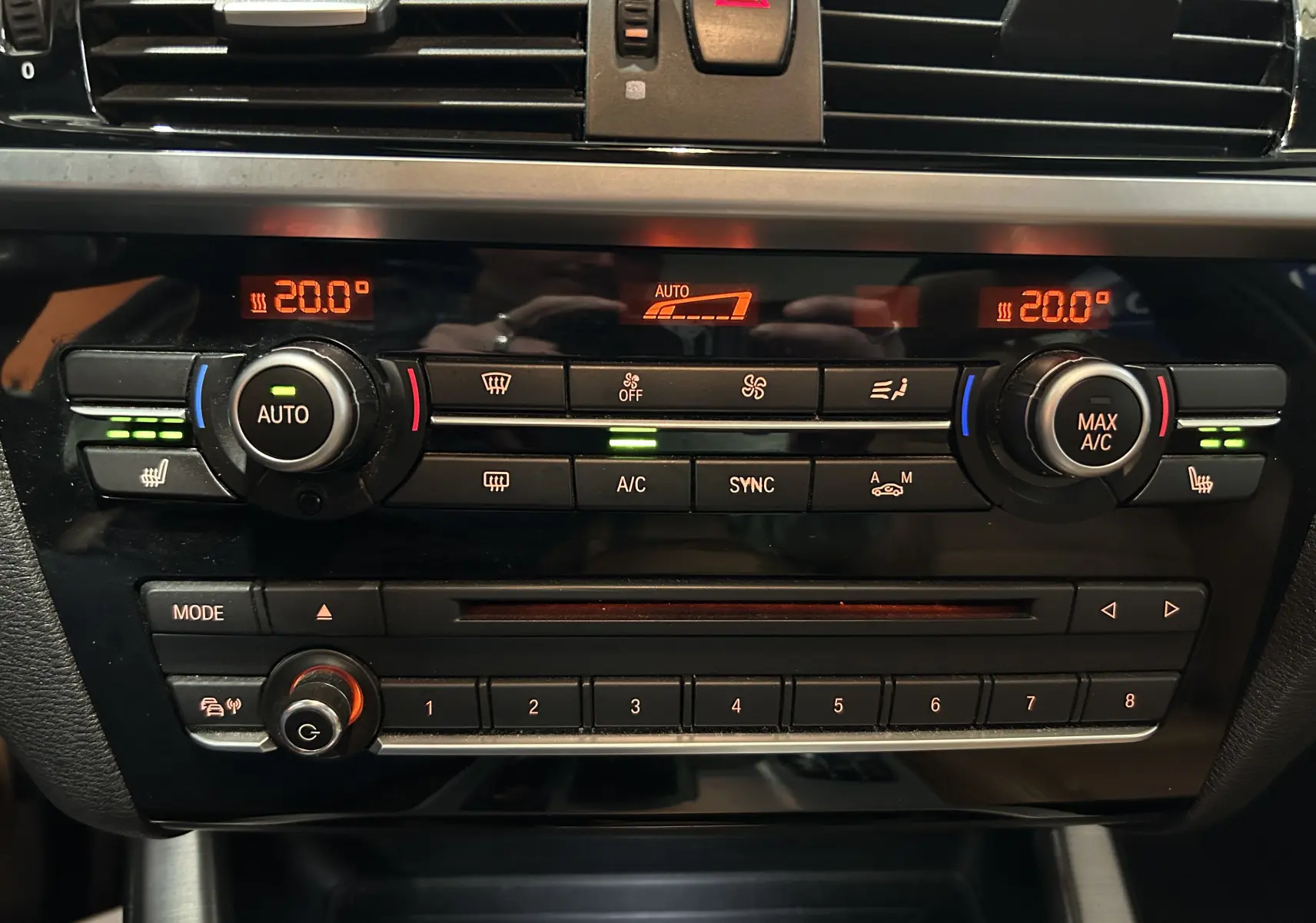 Gros plan sur la console centrale noire du BMW X3 2017, affichant la climatisation digitale à 20°C et commandes tactiles.
