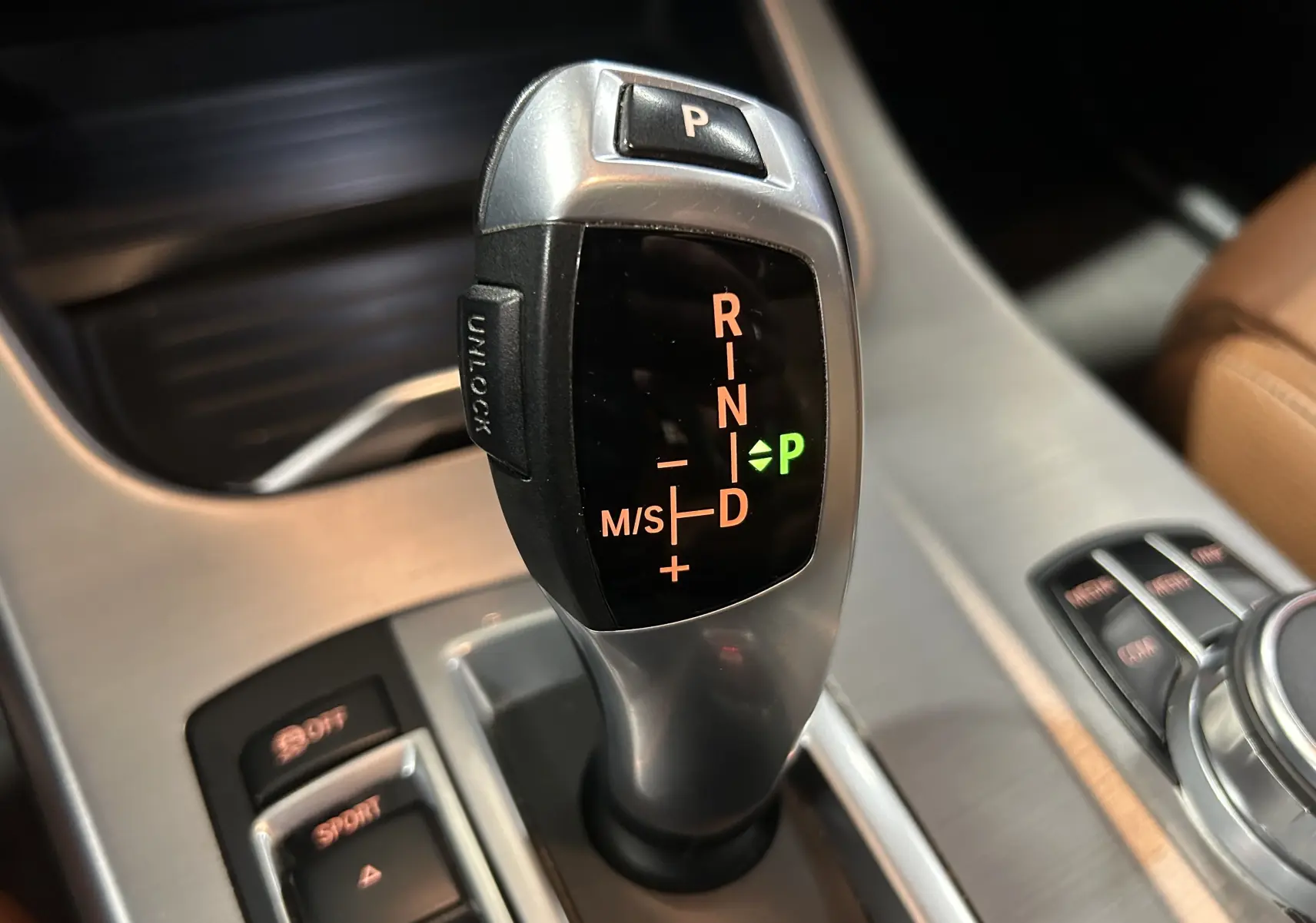 Gros plan sur le levier de vitesses automatique de la BMW X3 noir, avec indication du mode parking allumé.