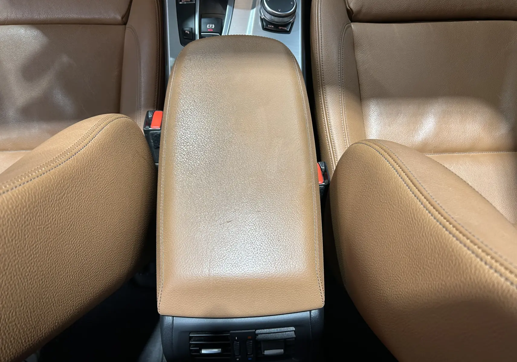 Vue plongeante sur l'accoudoir central en cuir marron et les sièges avant du BMW X3 sDrive18dA 2017.