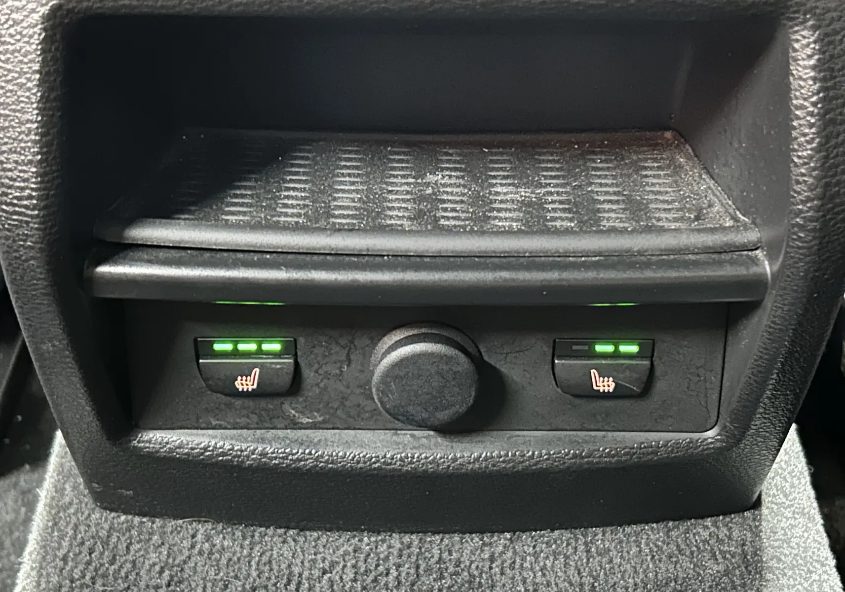 Gros plan sur les commandes des sièges chauffants arrière du BMW X3 noir, avec voyants verts allumés.