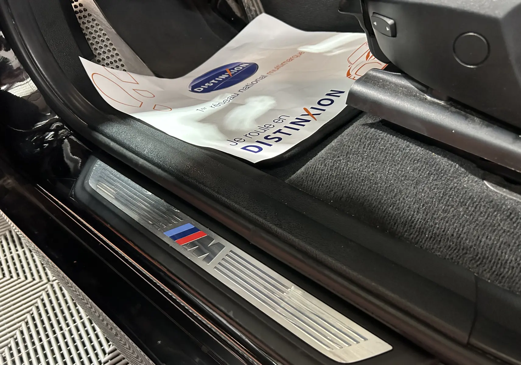 Détail de la plaque de seuil de porte M sur le côté gauche d’un BMW X3 noir, intérieur avec tapis et protection papier.