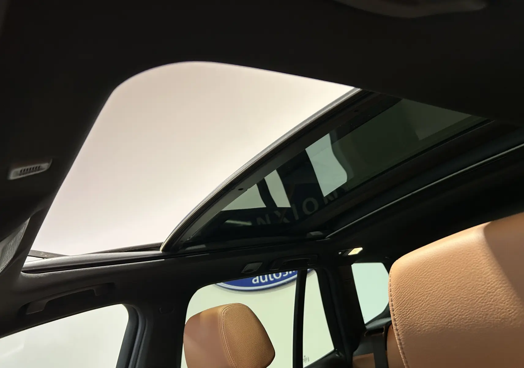 Vue intérieure du toit ouvrant panoramique ouvert et des sièges en cuir marron du BMW X3 noir 2017.