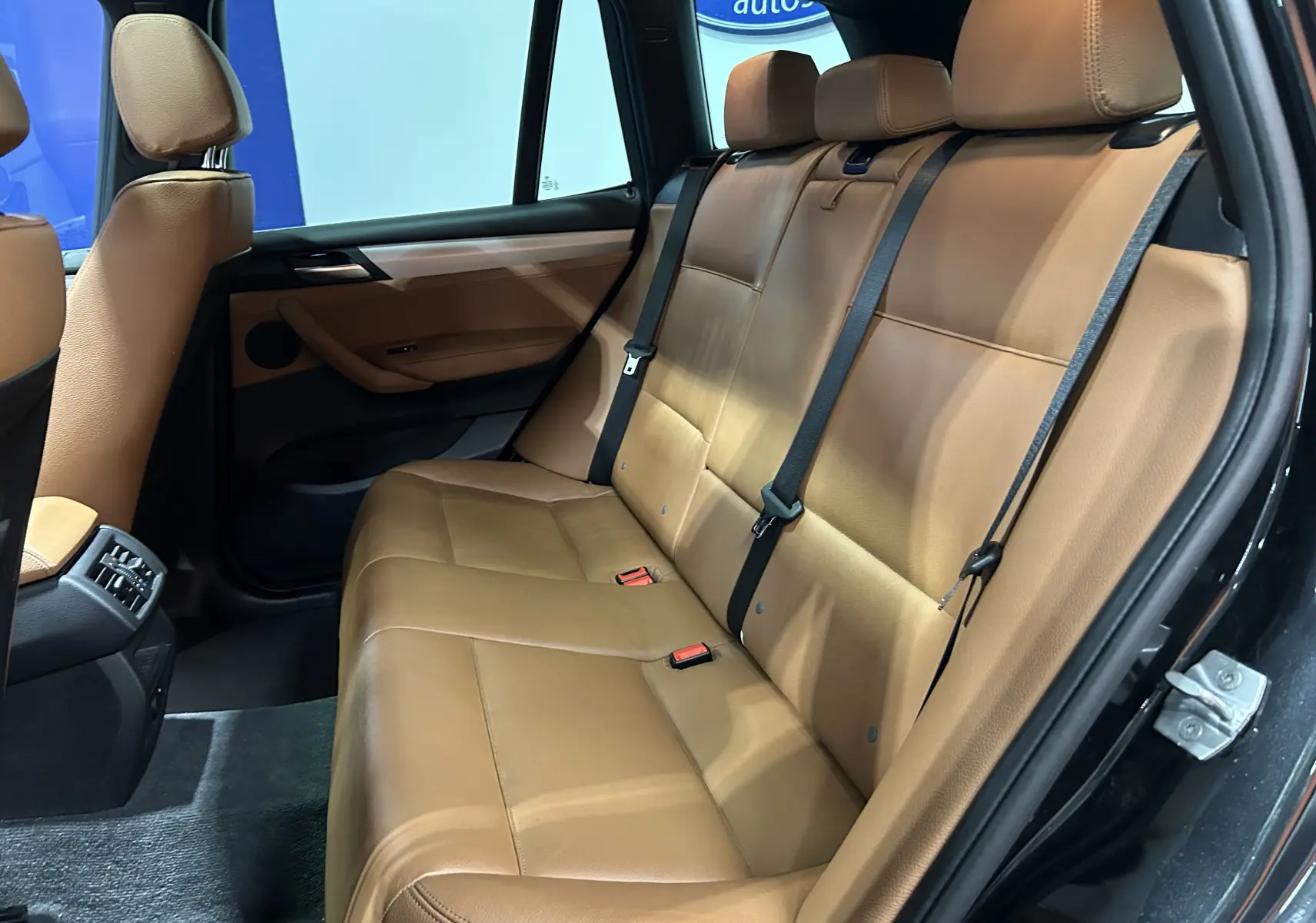 Vue intérieure côté droit montrant la banquette arrière en cuir marron du BMW X3 noir de 2017.