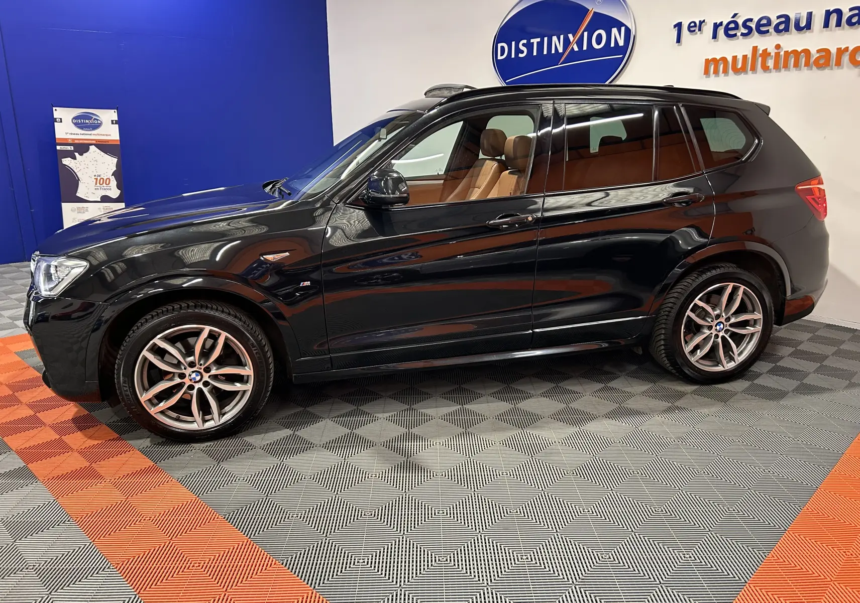 BMW X3 sDrive18d noir en vue profil côté gauche, intérieur cuir marron visible, jantes alliage et toit ouvrant.