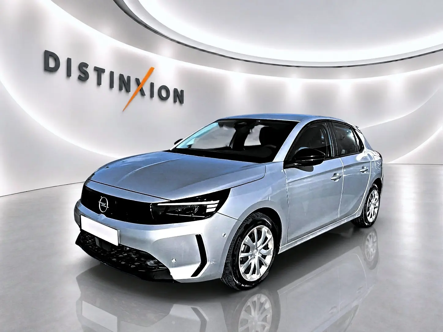 Opel Corsa gris alu vue 3/4 avant droit, avec calandre noire et jantes alliage visibles dans un showroom lumineux.