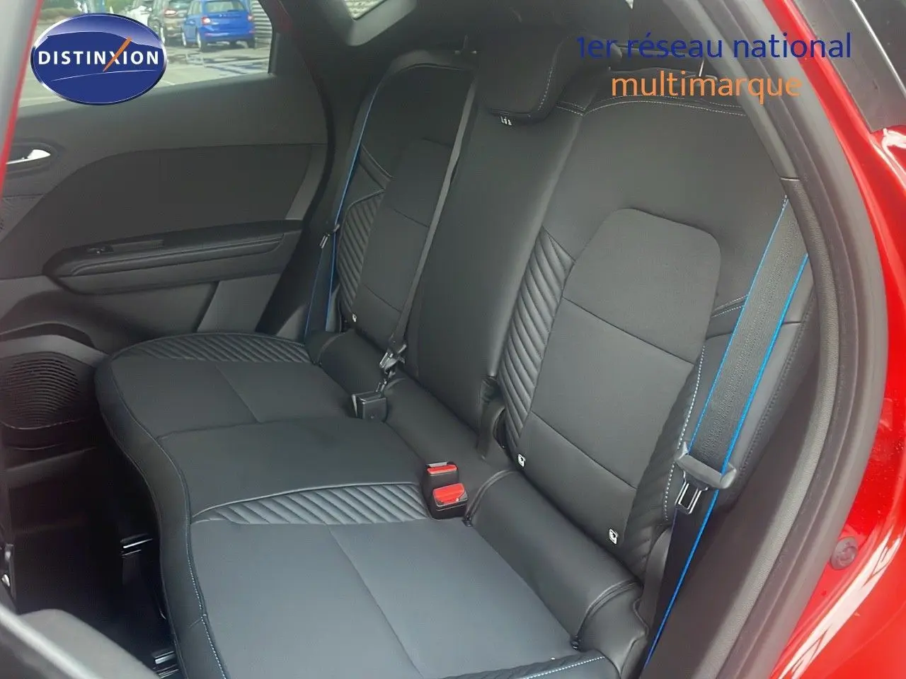 Vue intérieure arrière du Renault Captur rouge passion, sièges noirs avec surpiqûres bleues et ceinture assortie.