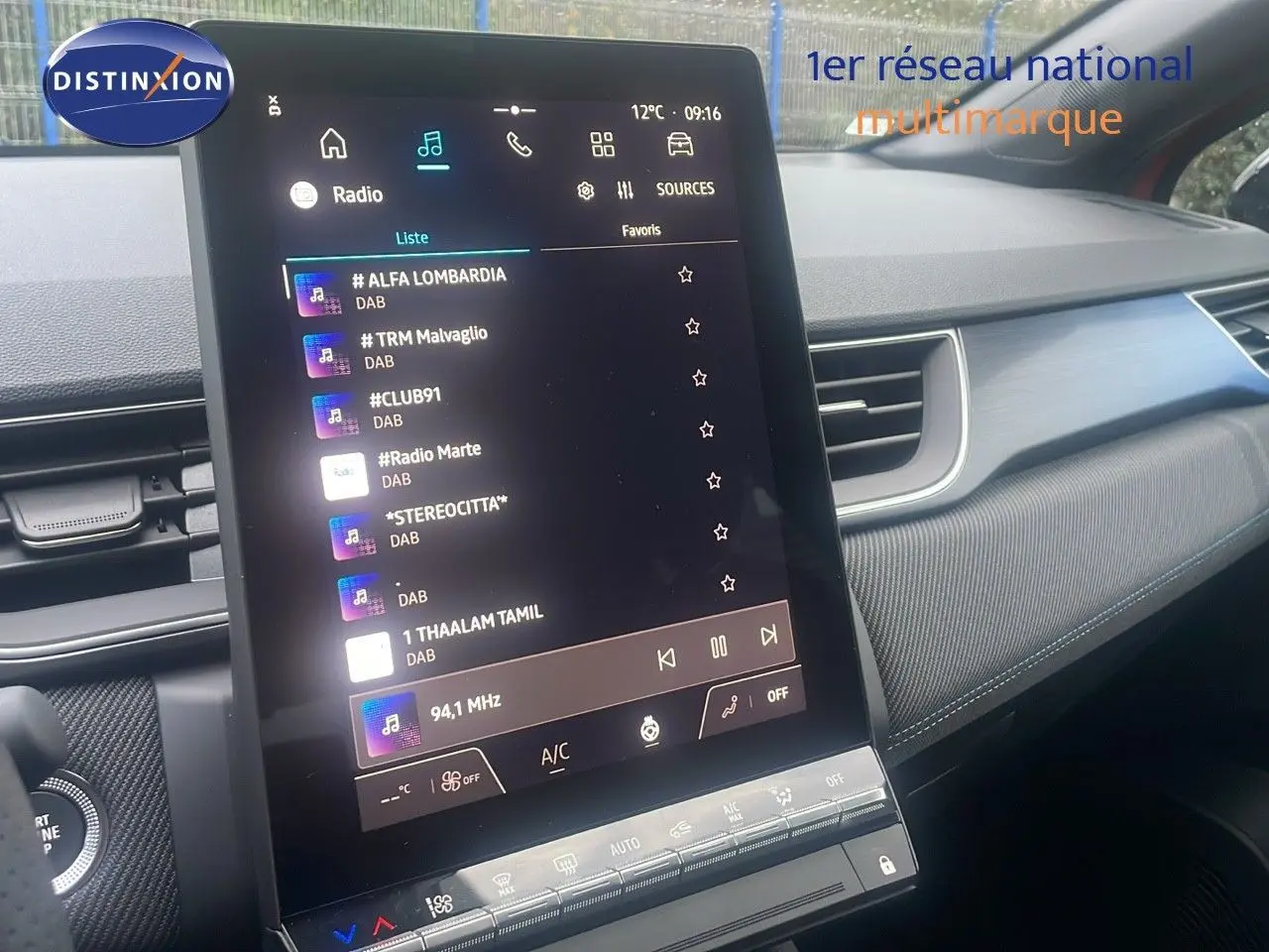 Vue intérieure centrée sur l’écran tactile vertical du tableau de bord du Renault Captur E-Tech rouge passion avec toit noir.