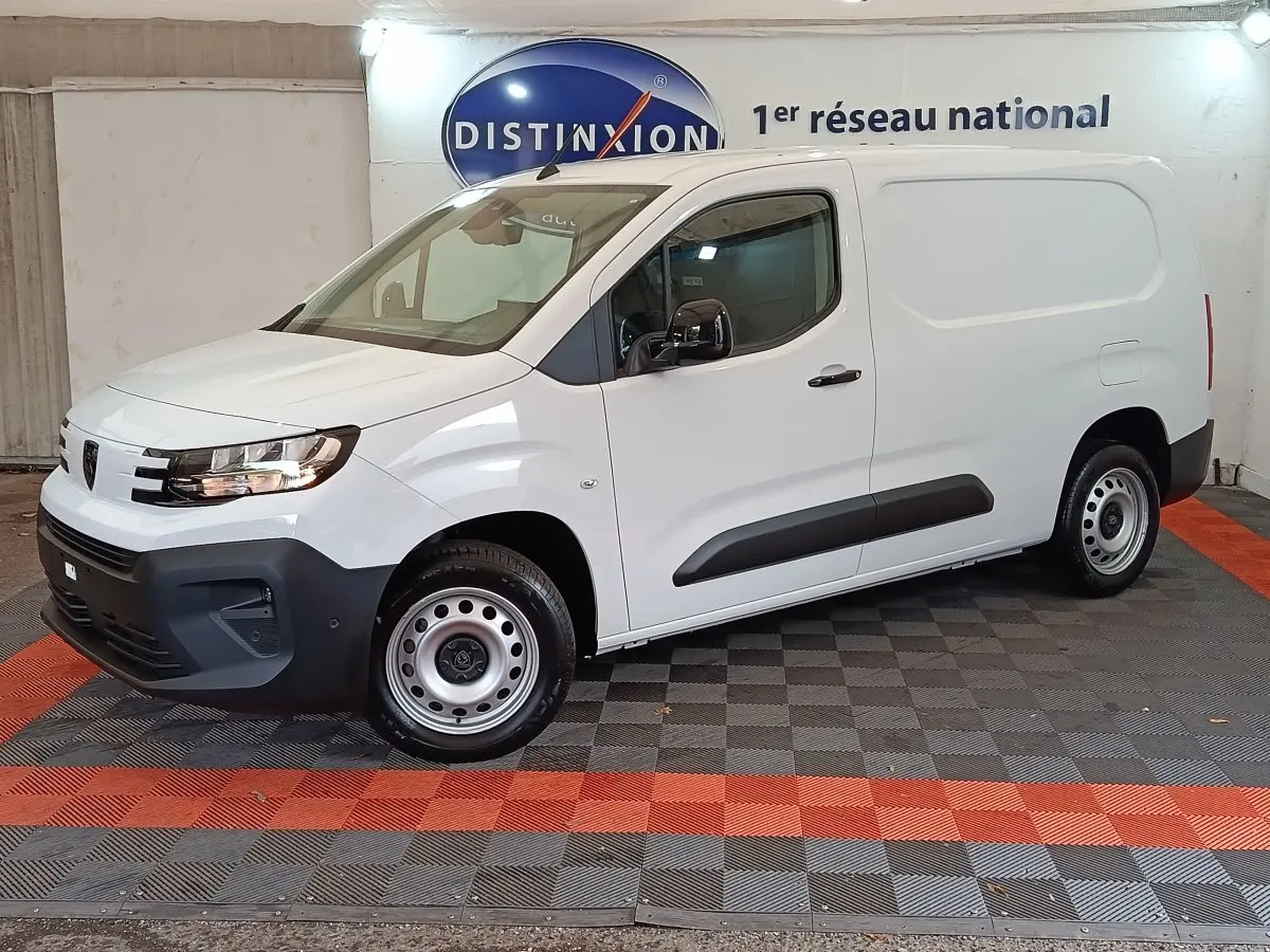 Vue de profil côté gauche d'un utilitaire Peugeot Partner XL blanc avec protections latérales noires en intérieur showroom.