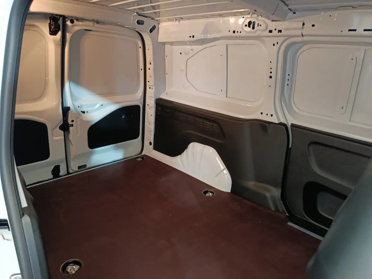 Intérieur du coffre blanc du Peugeot Partner XL 950kg vu de l'arrière gauche, montrant l'espace de chargement vide et les protections noires.