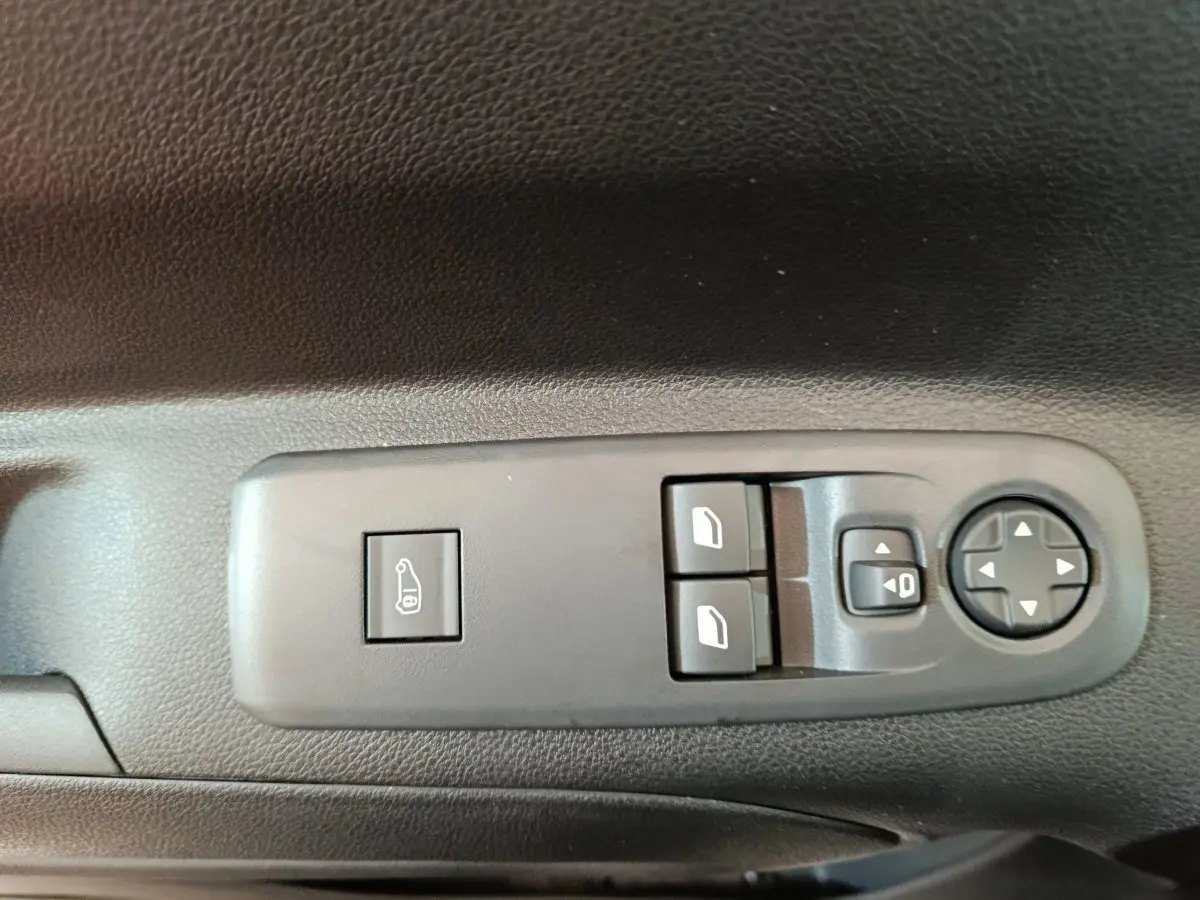 Gros plan sur les commandes de lève-vitres et réglage des rétroviseurs côté conducteur du Peugeot Partner blanc 2025.