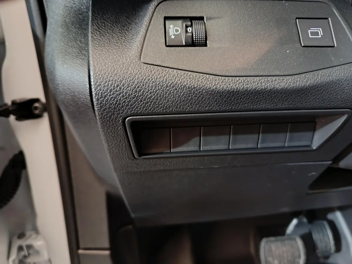 Détail du tableau de bord noir du Peugeot Partner XL 2025, avec commandes d'éclairage et boutons vides visibles.