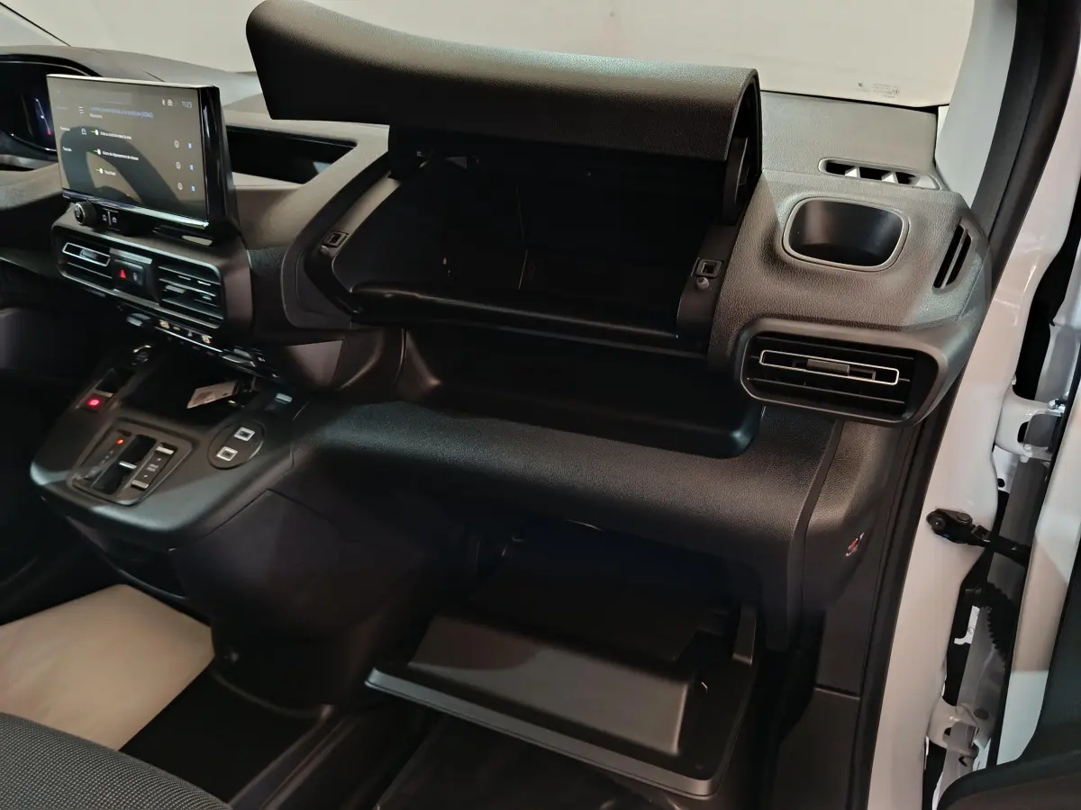 Vue intérieure côté passager du tableau de bord noir du Peugeot Partner XL 2025 avec boîte à gants ouverte et écran tactile central.