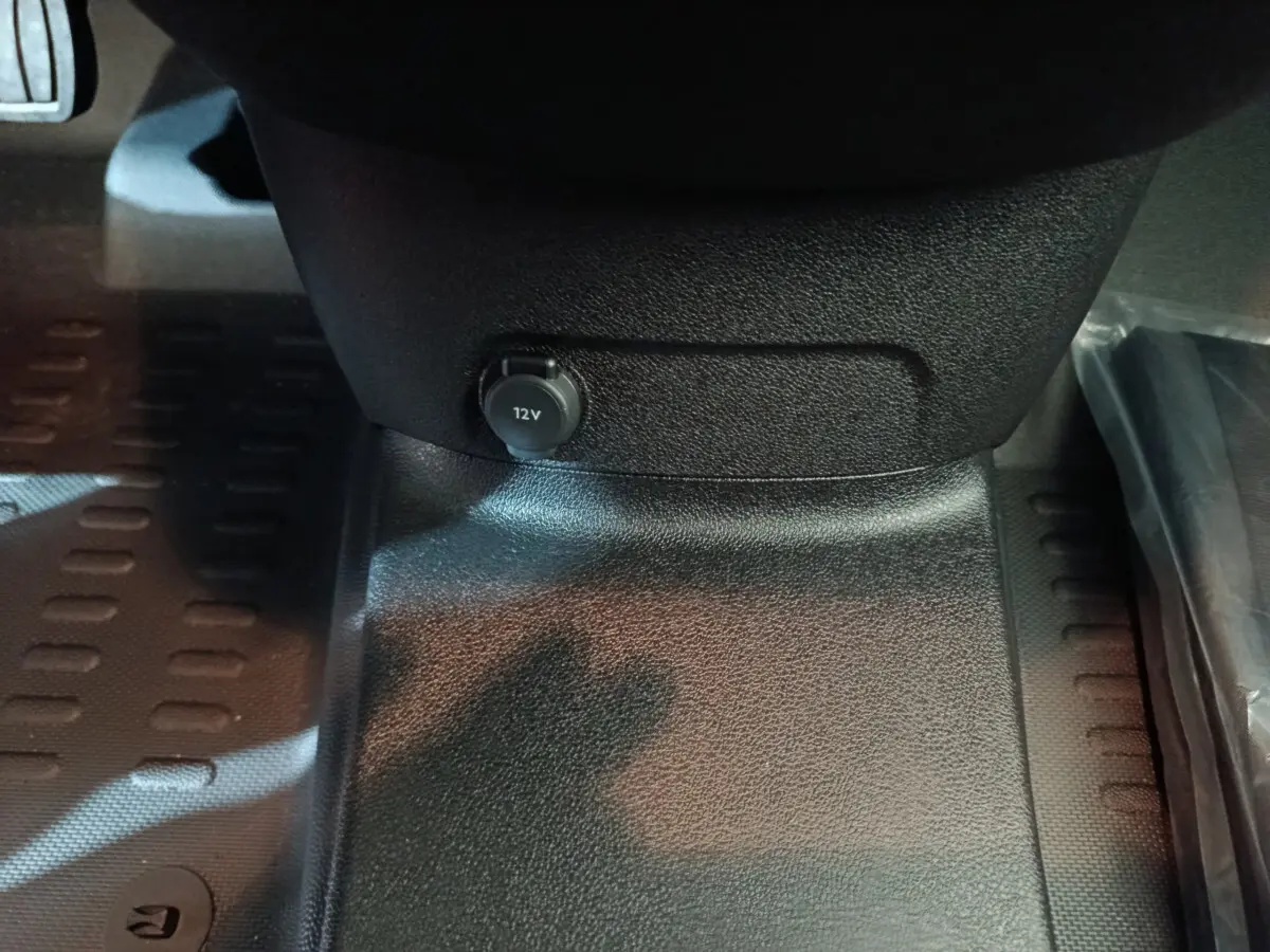 Prise 12V en gros plan sous le tableau de bord du Peugeot Partner XL blanc, intérieur noir texturé.