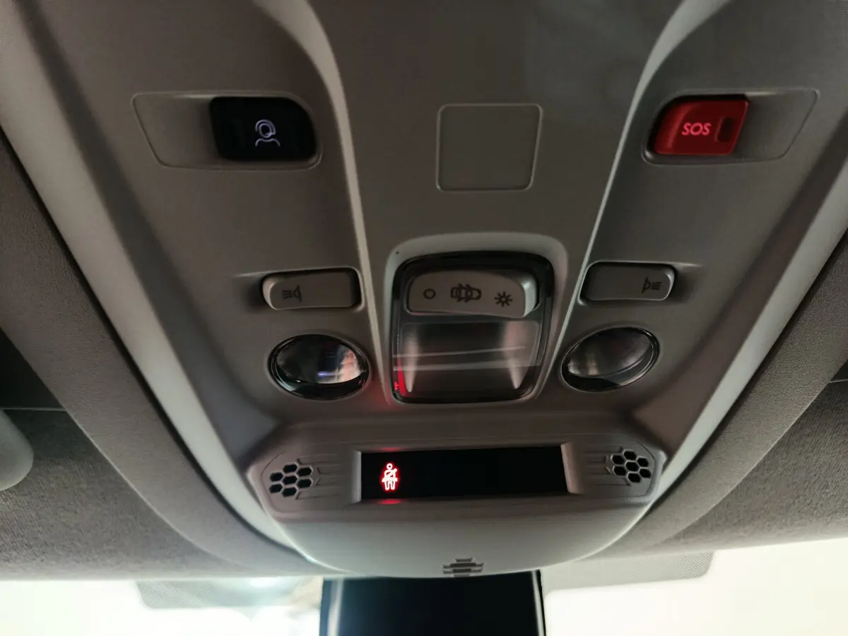 Vue en gros plan du panneau de commande au plafond intérieur du Peugeot Partner blanc, avec bouton SOS rouge et éclairage intégré.