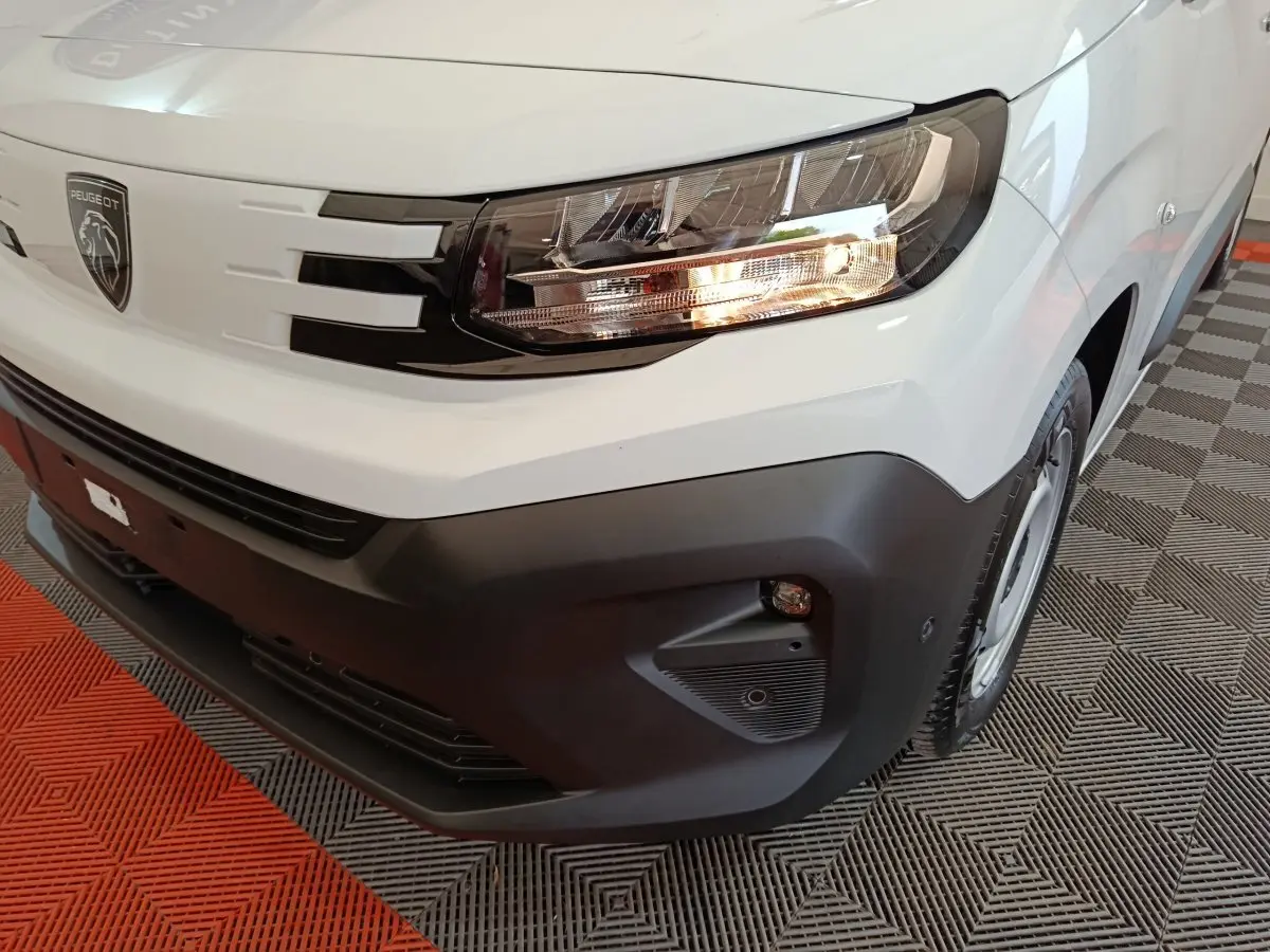 Gros plan sur le phare avant droit et la calandre noire du Peugeot Partner XL blanc, avec pare-chocs noir mat.
