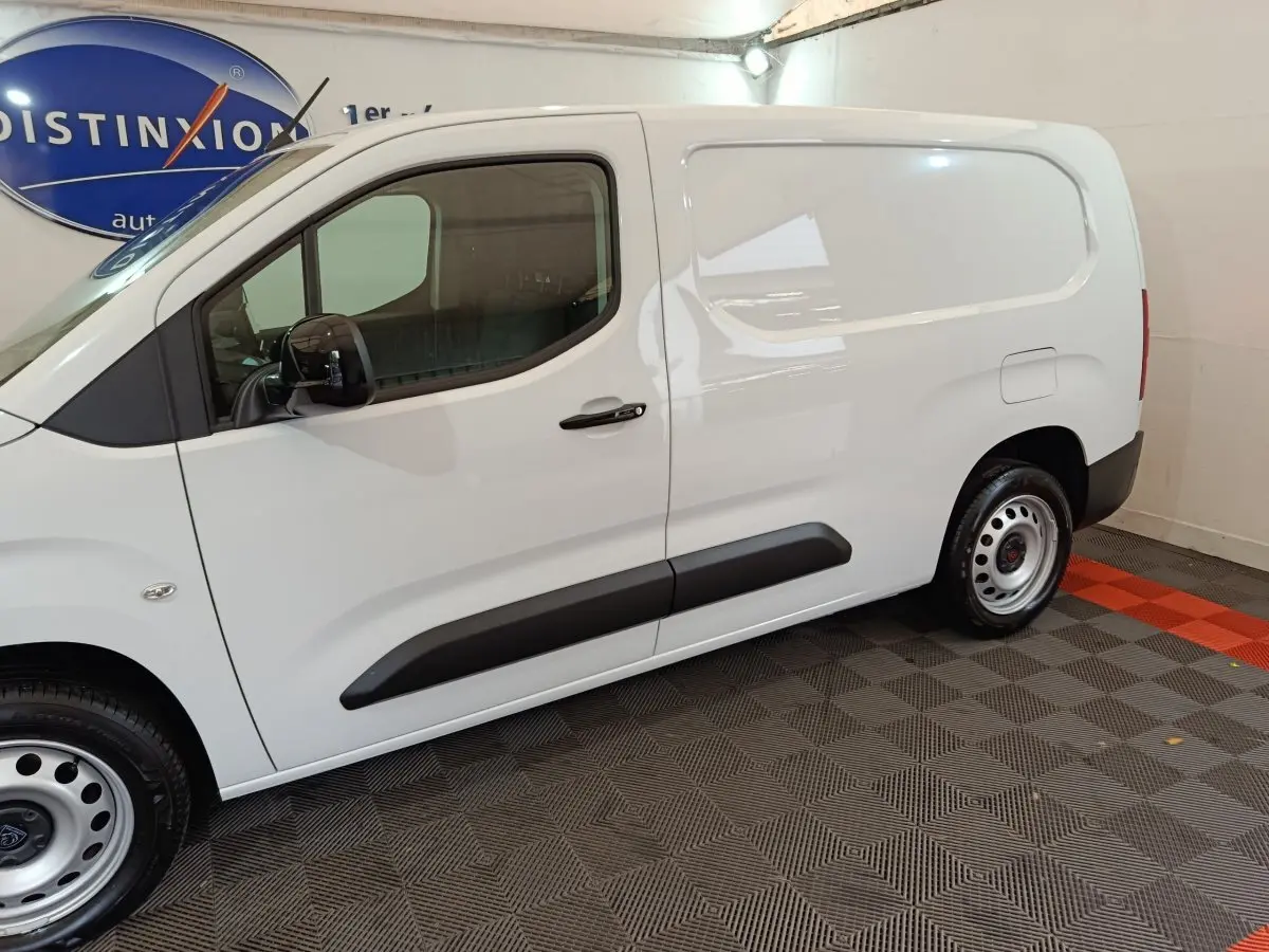 Vue de profil côté gauche d'un utilitaire blanc Peugeot Partner XL 950kg avec portes latérales pleines et jantes acier.