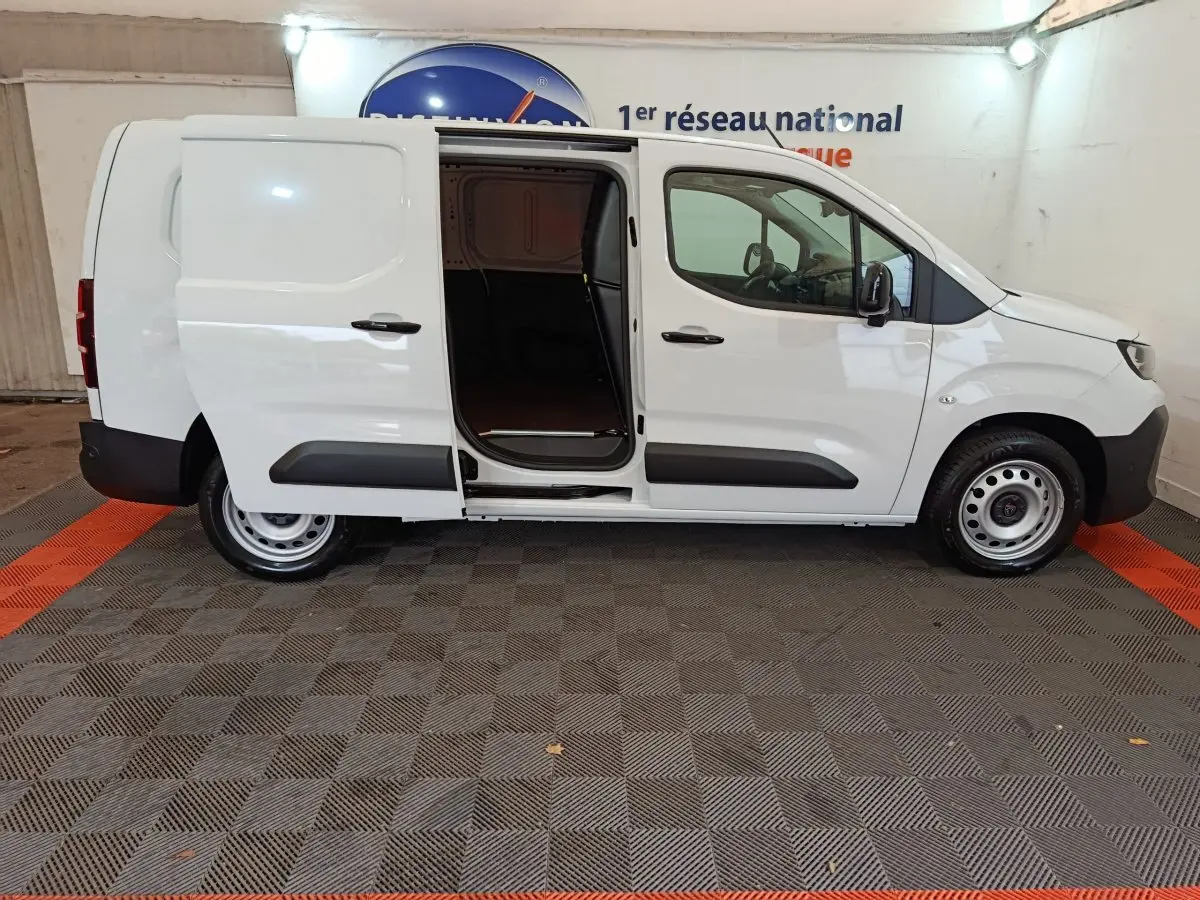 Vue de profil côté droit d’un Peugeot Partner blanc 2025 avec porte latérale coulissante ouverte montrant l’espace de chargement.