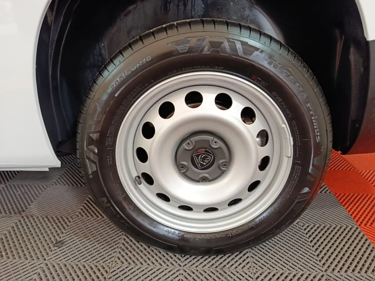 Gros plan sur la roue avant droite du Peugeot Partner blanc 2025, mettant en valeur la jante acier et le pneu Vava.